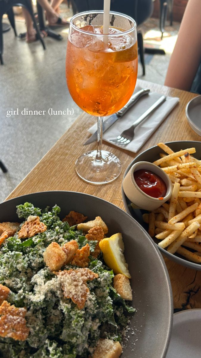 a bowl of food next to a plate of fries and a drink on a table