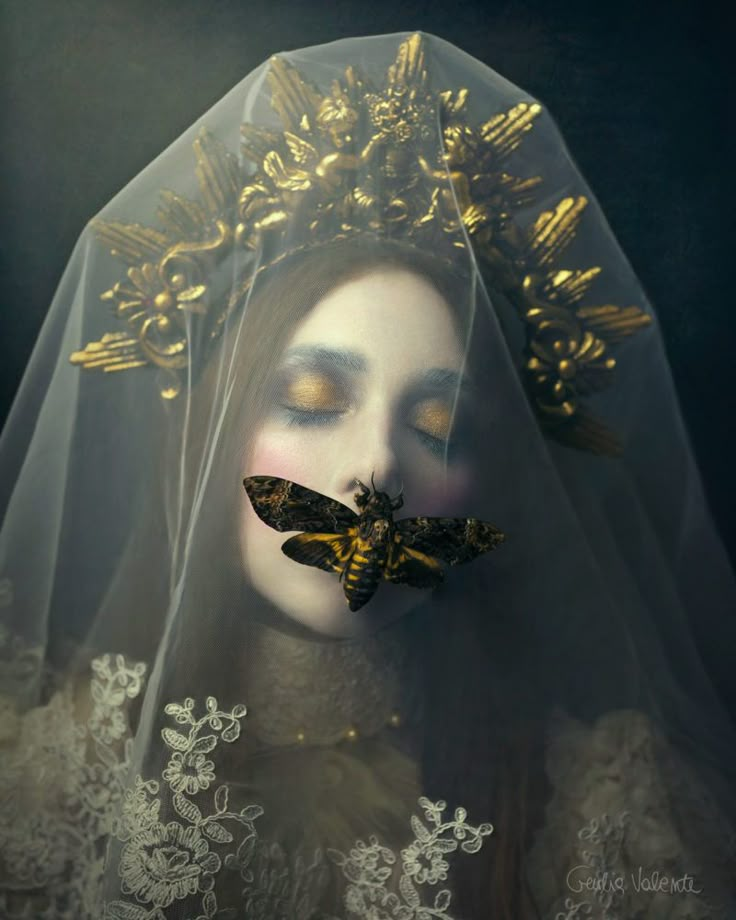 a woman wearing a veil with a butterfly on it's nose and gold eyeshadow