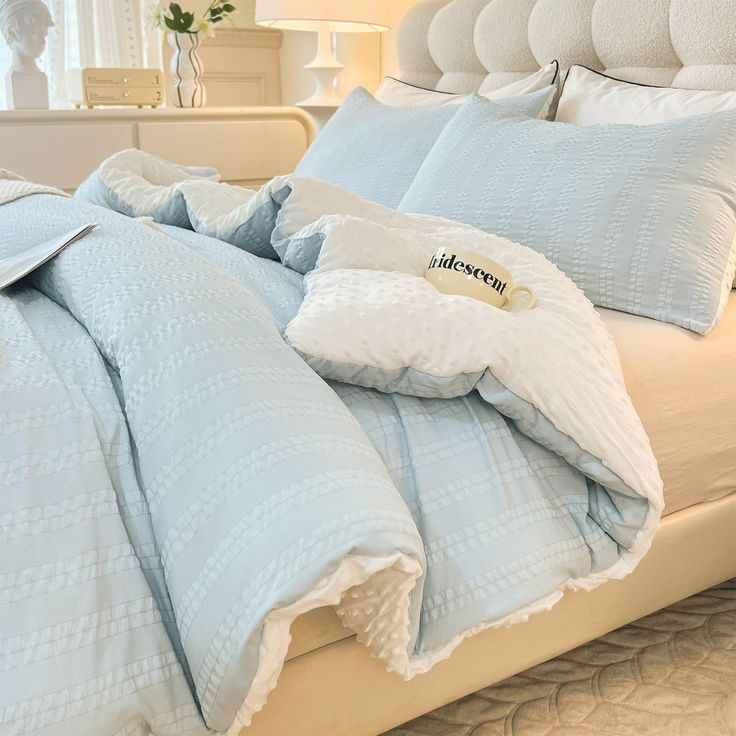 an unmade bed with blue sheets and pillows