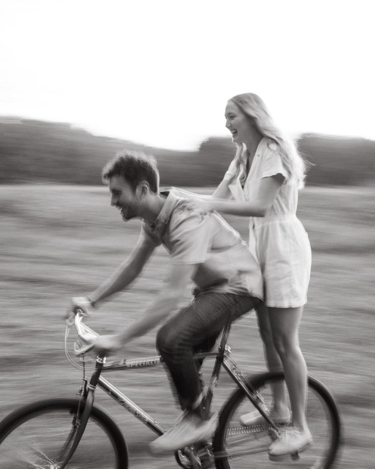 a man and woman riding on the back of a bike