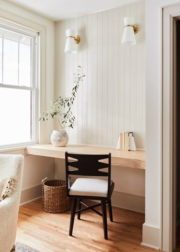 a white chair sitting in front of a window next to a wooden table with a potted plant on top of it