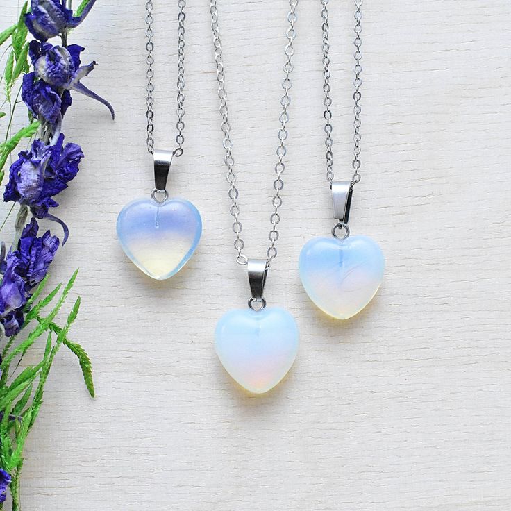 This necklace is made from a opalite stone which has been cut into a puffy heart. The stone hangs from a silver plated chain. You can choose the length of the necklace you prefer. You will get a necklace at random. Please note that all necklaces are handmade and may differ from the pictured. The picture shows multiple necklaces. You will receive one necklace with one pendant. Ewelina Pas Jewelry White Heart-shaped Moonstone Jewelry, White Heart-shaped Crystal Necklace Gift, White Heart-shaped Crystal Necklace For Gift, Silver Crystal Necklace With Heart Beads For Gift, Silver Heart Moonstone Necklace, Silver Heart-shaped Moonstone Necklace, Gold Gemstone Necklace, Heart Necklace Silver, Necklace Layering