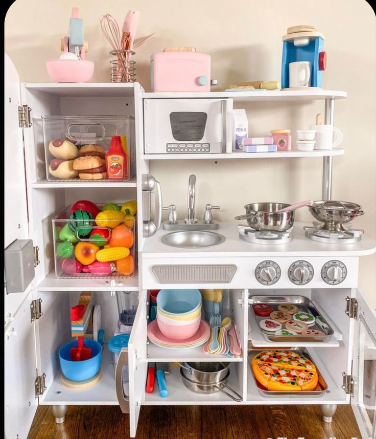 a play kitchen with lots of toys and food on the shelves in front of it