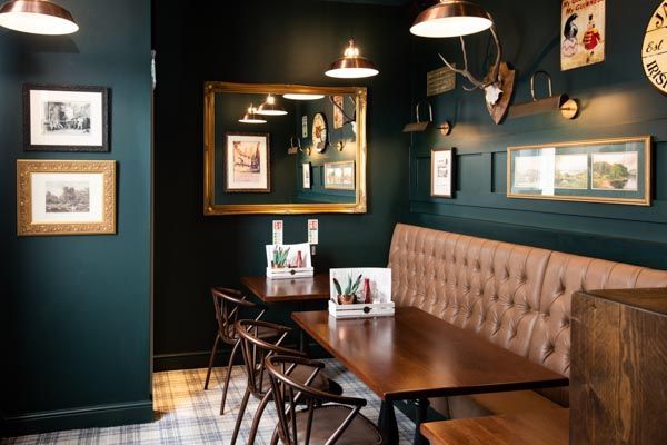 a restaurant with green walls and wooden tables in the center, along with pictures on the wall