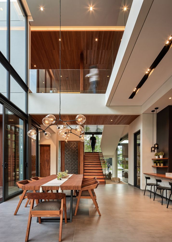 a dining room table with chairs and lights hanging from it's ceiling, next to an open floor plan