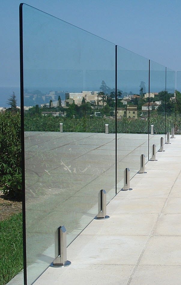 a row of metal posts on the side of a road next to grass and trees