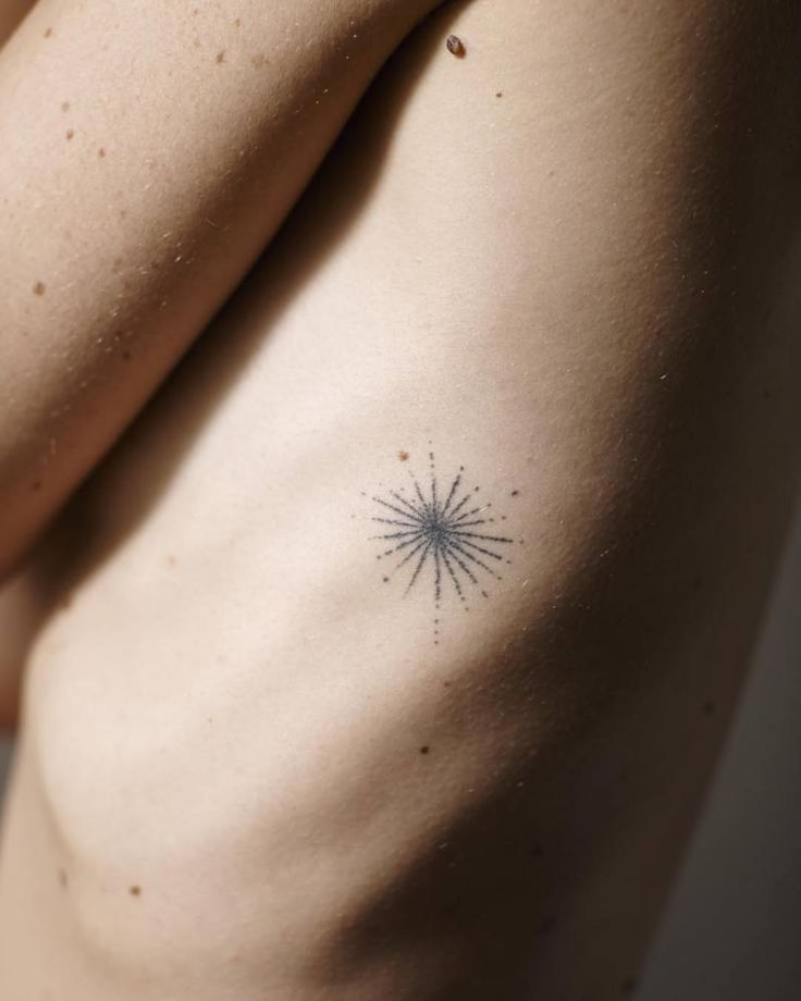 a woman's breast with a small star tattoo on her left side ribcage