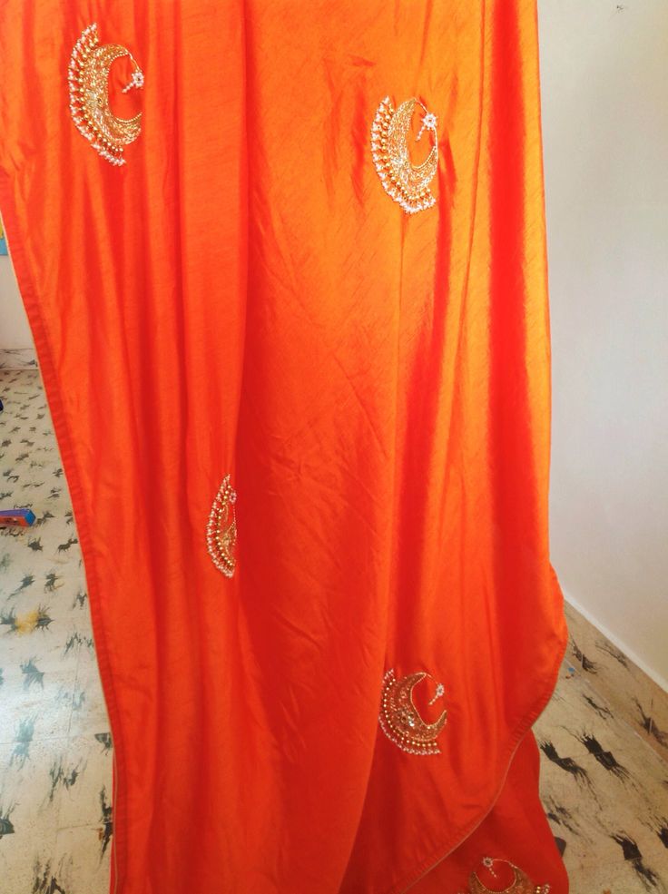 "Stunning orange semi silk saree with intricate all over chaandbali design hand embroidery and rawsilk tissue offwhite unstiched blouse with matching necklace embroidery atvthe neck and handworked sleeve borders. The embroidery on the saree is just beautiful, classy and truly a work of art. And, guess what, you dont need a neck piece to go with this. The fantastic embroidery on the blouse is so beautiful and makes this a unique piece. Saree length 5.5 meters Blouse fabric 1 meter 44\" wide Saree Traditional Orange Art Silk Pre-draped Saree, Orange Pre-draped Saree With Pallu For Wedding, Orange Raw Silk Traditional Wear With Gota Work, Orange Pre-draped Saree With Dupatta For Festivals, Unstitched Orange Pre-draped Saree For Puja, Orange Pre-draped Saree For Wedding And Diwali, Designer Orange Dupatta With Resham Embroidery, Unstitched Orange Silk Lehenga, Orange Dola Silk Traditional Wear With Gota Work