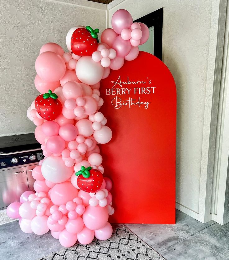 the balloon arch is decorated with strawberries and balloons