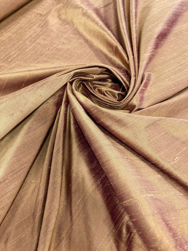 a close up view of the fabric in gold and purple tones on a plain background