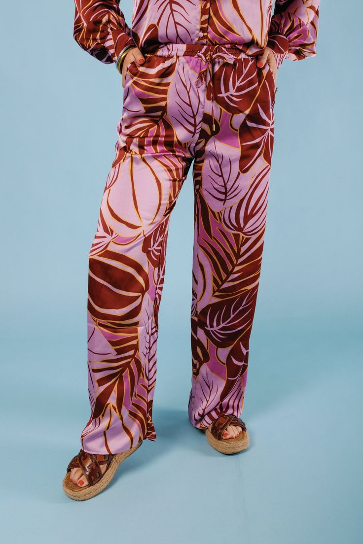 Add some playful flair to your wardrobe with The Tropical Satin Pants. Featuring a vibrant tropical print, these satin pants boast a stylish wide leg cut, perfect for any warm weather occasion. Stand out and make a statement in these quirky and fun pants that are sure to turn heads. Fabric Content: 100% POLYESTER Trendy Full-length Pants For Vacation, Trendy Pants For Vacation, Trendy Full Length Pants For Vacation, Pink High-waisted Wide Leg Pants For Vacation, Casual Summer Pants With Bold Print, Spring Tropical Print Pants, Tropical Printed Pants For Spring, Vacation Rayon Printed Pants, Vacation Printed Rayon Pants