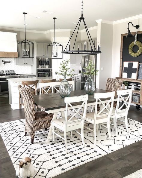 a dining room table with chairs and a dog sitting on the rug in front of it