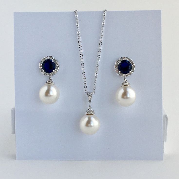 I've created this elegant blue sapphire cubic zirconia and pearl bridal jewelry set in rhodium plated brass setting and the set includes: # Earrings feature large 12mm Swarovski pearls that dangle from brilliant cut blue sapphire cubic zirconia with halo setting 12mm ear stud. Halo setting gives a brilliantly beautiful effect. Total length of the earrings is 2.8 cms. #Classic pearl bridal necklace and pendant set with rhodium plated brass peg and bail. Necklace features a pendant with large 12mm Sapphire Jewelry Sets For Wedding, Sapphire Cubic Zirconia Jewelry For Wedding, Sapphire Cubic Zirconia Wedding Jewelry, Formal Pearl Drop Jewelry Sets With Cubic Zirconia, Formal Blue Jewelry With Pearl Pendant, Formal Blue Pearl Pendant Jewelry, Blue Pearl Drop Wedding Jewelry, Blue Pearl Drop Jewelry For Wedding, Blue Pearl Pendant Jewelry For Wedding