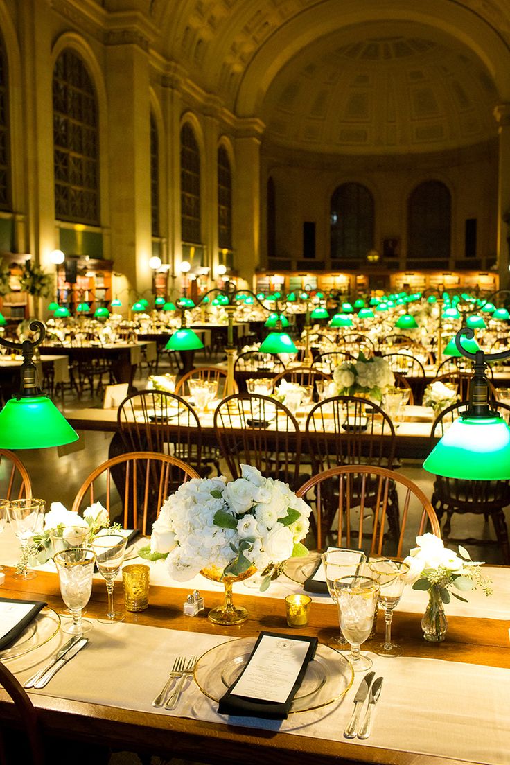 tables and chairs are set up in the dining hall for a formal function with green lamps