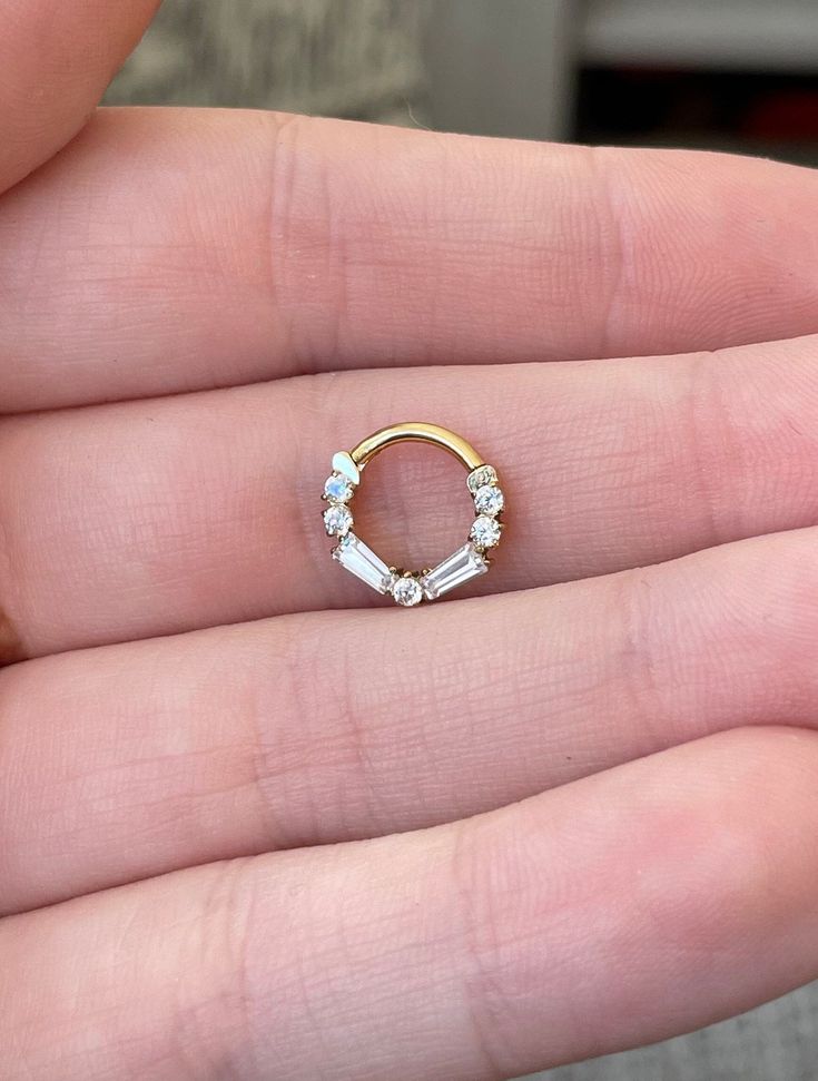 a woman's hand holding a gold ring with three stones on the inside and outside