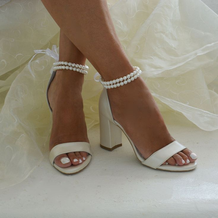 a close up of a person wearing high heel shoes and pearls on their ankle straps