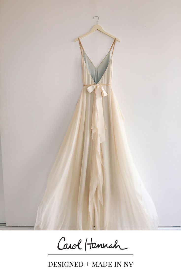 a dress hanging on a wall with a hanger in front of it that has a bow at the waist