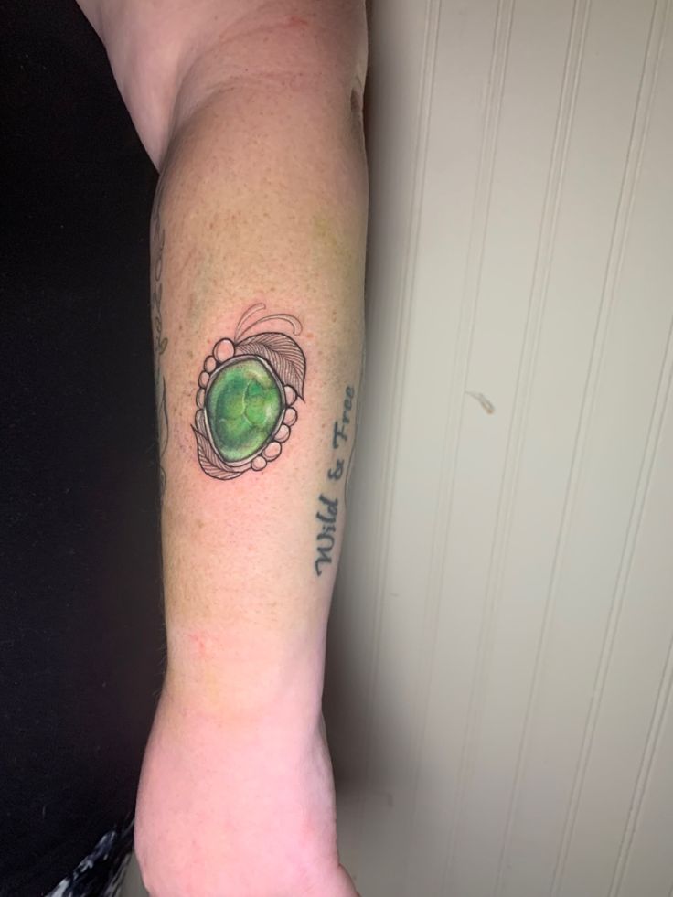 a woman with a green ring tattoo on her arm