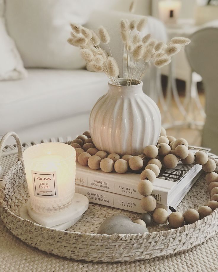 a white vase sitting on top of a table next to a candle and some books