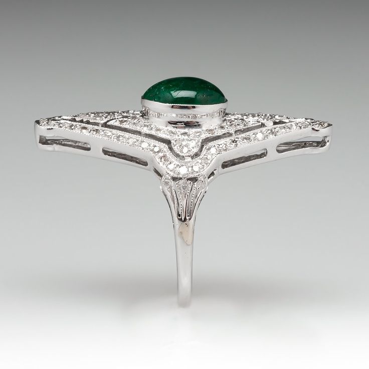 This exquisite ring features a pierced design, centered with an oval, emerald cabochon, weighing 1.75 carats, in a full bezel setting, accented with milgrain details. The top of the ring is accented with one hundred six (106) bead set, round single cut diamonds. The ring measures 31.9mm at the top, rises 8.0mm above the finger, tapering to 1.5mm wide and 0.8mm thick at the base of the shank. This ring is currently a size 5.75. The emerald has surface reaching natural inclusions. Fine Jewelry Emerald Oval Cabochon Ring, Fine Jewelry Emerald Ring With Oval Cabochon, Green Oval Emerald Ring In Platinum, White Gold Oval Emerald Ring Art Deco Style, Emerald Oval Cabochon Ring In Fine Jewelry Style, Luxury Emerald Ring With Oval Cabochon And 17 Jewels, Luxury Oval Cabochon Emerald Ring With 17 Jewels, Luxury Emerald Ring With Oval Cabochon, Exquisite Oval Emerald Ring In Platinum