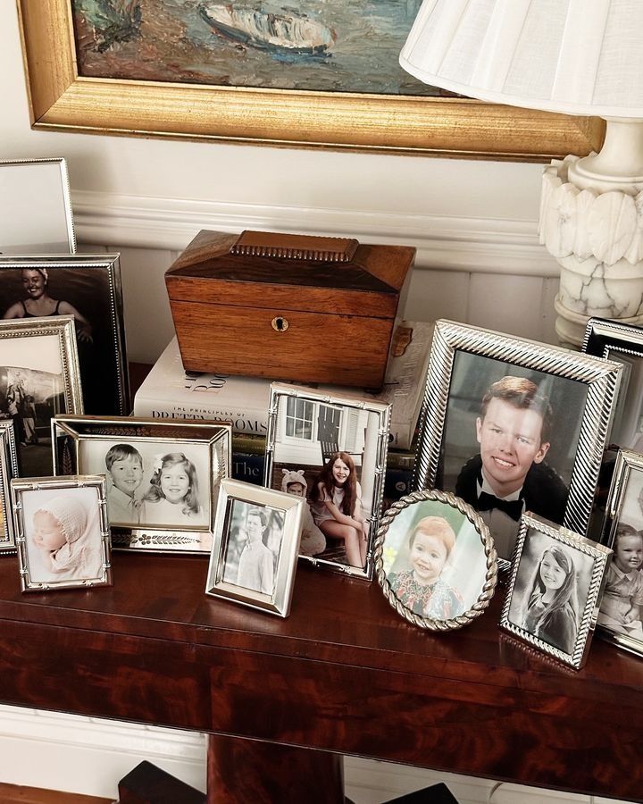 a wooden table topped with lots of framed pictures