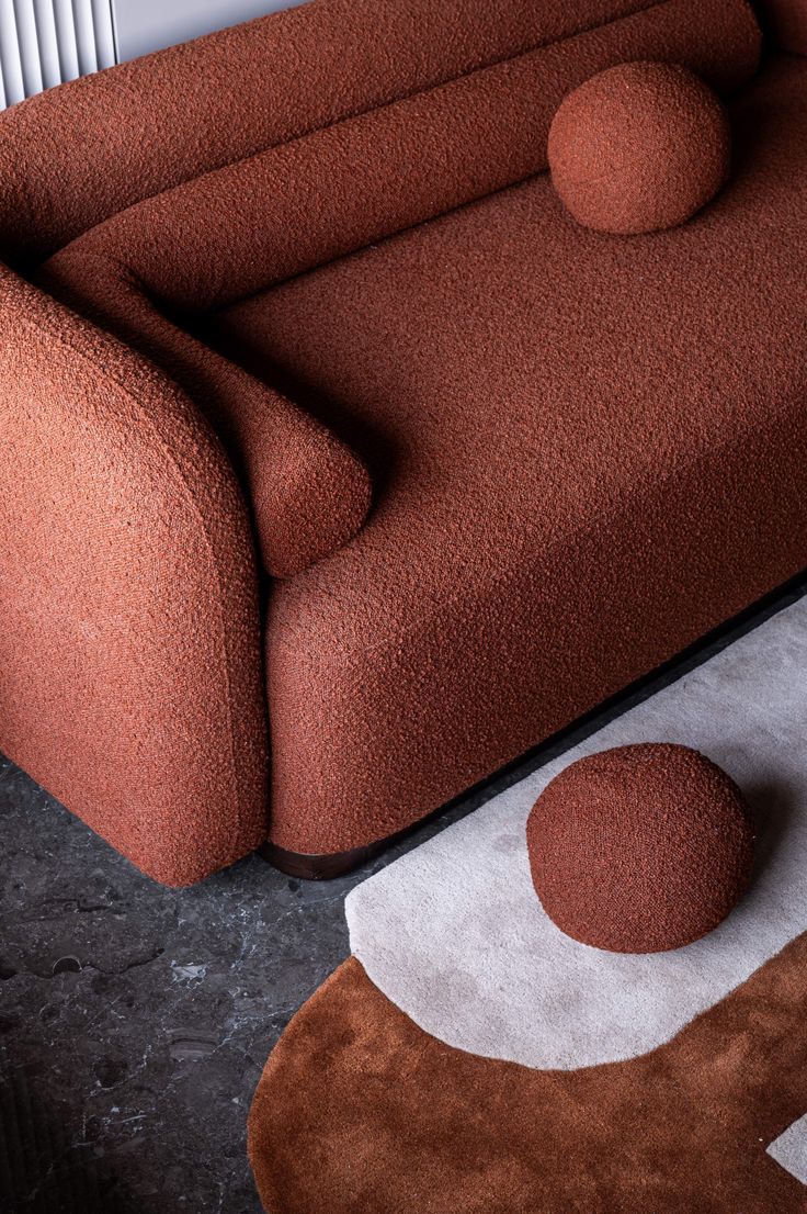 a brown couch sitting on top of a rug next to a white and black table