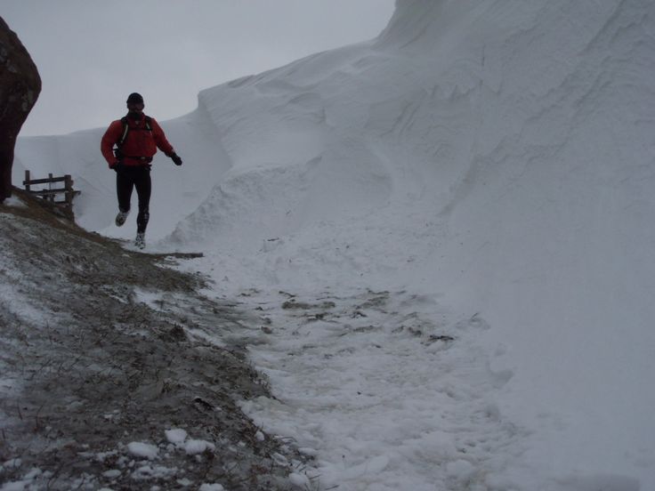 a man walking up a snow covered hill