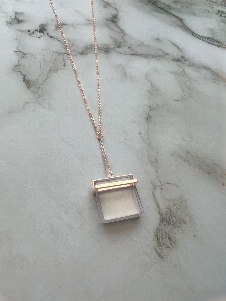 This stunning necklace features a square clear quartz crystal pendant that dangles gracefully from a sterling silver chain with a 14K rose gold plating. The combination of the clear crystal and the warm rose gold create a beautiful contrast that adds elegance and sophistication to any outfit. The quartz crystal is known for its healing properties, making this necklace not only a stylish accessory, but also a meaningful piece of jewelry that can be worn for any occasion. 925 Sterling Silver Rose Chic Rose Gold Charm Necklace For Gift, Elegant Rose Gold Crystal Necklace With Delicate Chain, Rose Gold Sterling Silver Pendant Crystal Necklace, Elegant Clear Necklaces With Adjustable Chain, Rectangular Rose Gold Sterling Silver Jewelry, Minimalist Rose Gold Crystal Pendant Necklace, Rose Gold Pendant Necklace With Box Chain, Elegant Clear Jewelry With Adjustable Chain, Elegant Rose Gold Crystal Necklaces With Adjustable Chain