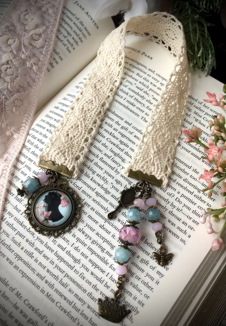 two necklaces are laying on top of an open book with flowers in the background