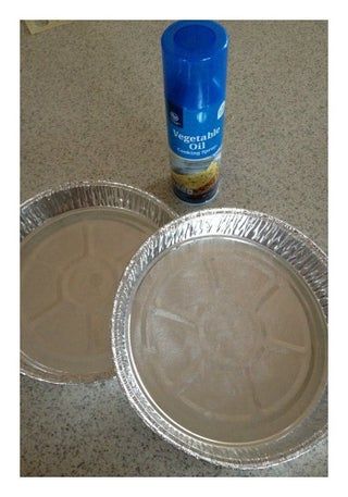 two aluminum pans sitting on top of a counter next to a can of beer