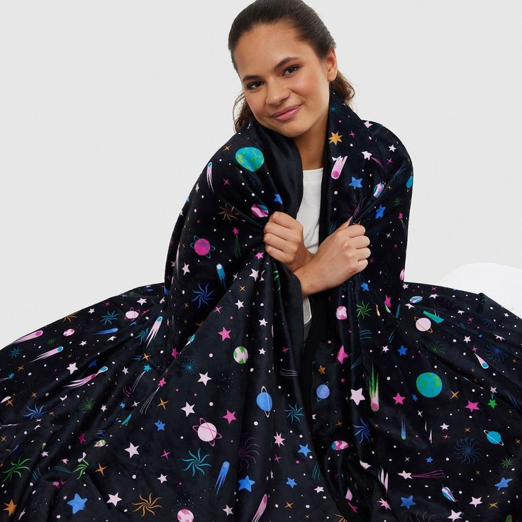 a woman in a black dress with stars and planets on it, posing for the camera