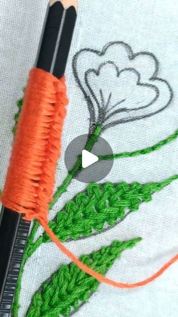 two pencils are sitting next to an orange thread on a piece of fabric that has been stitched together