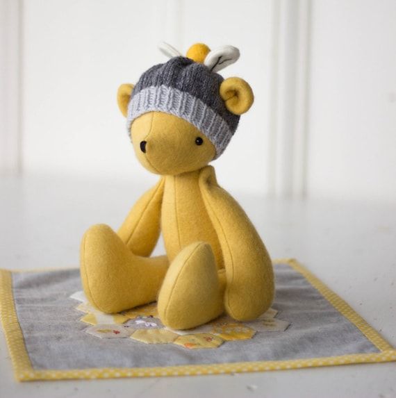 a small yellow teddy bear sitting on top of a table next to a white wall