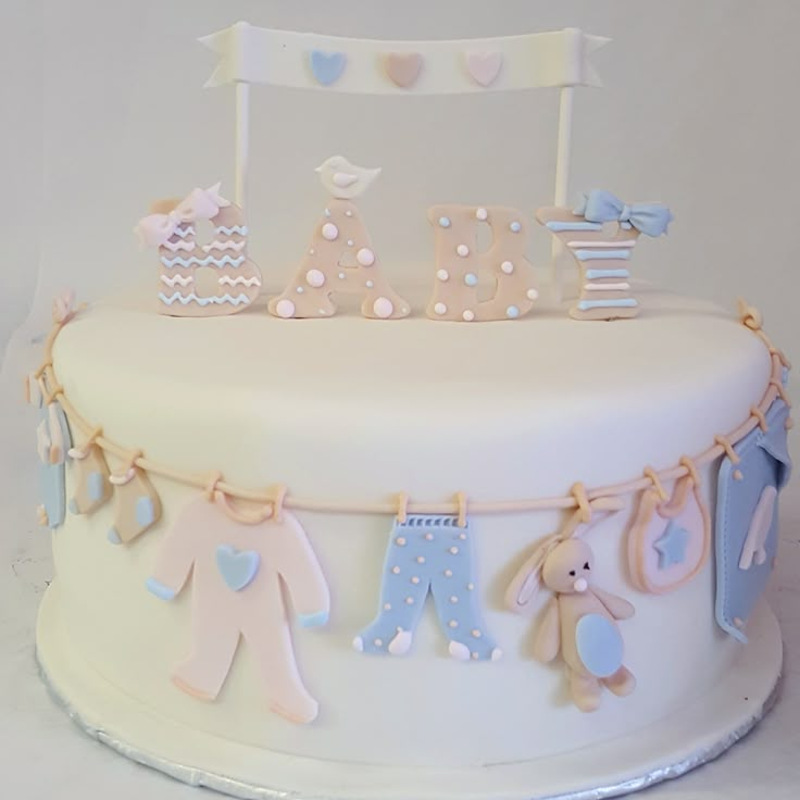 a baby shower cake with teddy bears and clothes hanging from it's sides on a white table