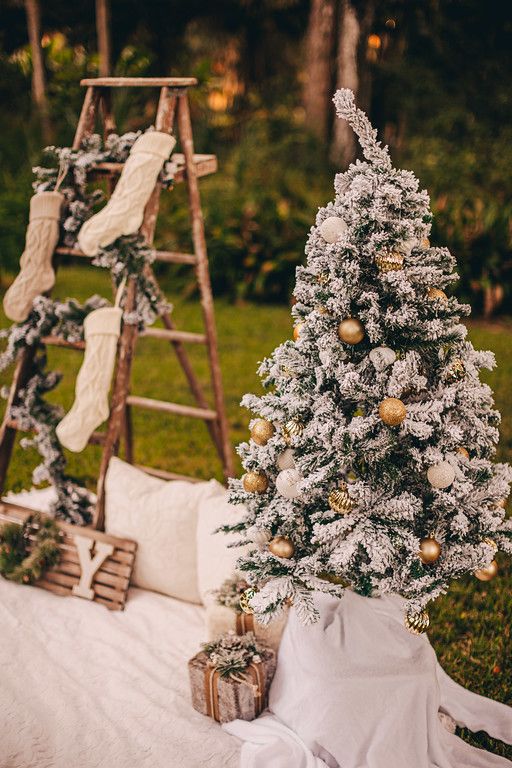 a small christmas tree sitting on top of a white blanket next to a wooden ladder