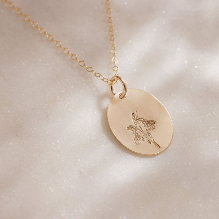 Delicate with a touch of whimsy, this hand-stamped pendant necklace features a flower design that represents your birth month. From the petite snowdrops of January to the classic holly of December, every month is represented (and some with two), making the Birth Month Necklace a great gift for moms, grandparents and friends, or any nature lover in your life. We love the subtle femininity it offers on its own, but because the oval pendant is suspended from a dainty gold chain that falls just belo Delicate Hand Stamped Necklace For Gift, Elegant Hand Stamped Pendant Necklace, Elegant Hand Stamped Pendant Charm Necklaces, Elegant Everyday Charm Necklace With Birth Flower, Delicate Personalized Flower Necklace, Dainty Engraved Flower Charm Necklace, Dainty Flower-shaped Engraved Charm Necklaces, Dainty Engraved Flower Charm Necklaces, Delicate Engraved Charm Necklace