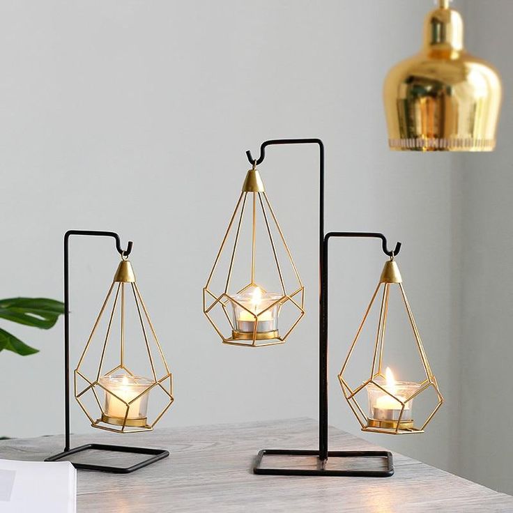 three candles are sitting on stands next to a potted plant