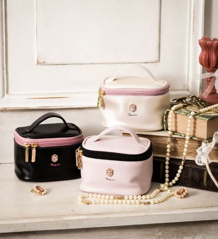 three purses sitting on top of a table next to some pearls and other items