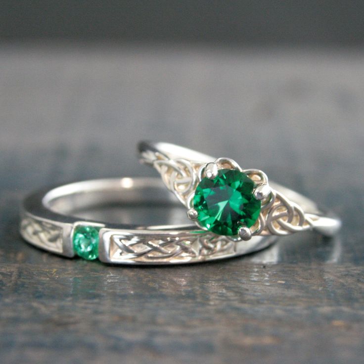 two wedding rings with green stones on them