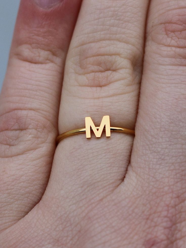 This elegant gold initial ring is perfect for stacking, making it a great gift for any occasion - whether a mother's day surprise or a best friend's birthday present. Crafted from quality stainless steel, this letter ring will look beautiful for years to come. Featuring a letter of your choosing, this ring can be worn alone or stacked making it perfect for gifting to friends or family. The subtle, yet sweet letter ring looks elegant alone or as part of a larger stack. This gold letter ring is th Dainty Gold Stackable Rings With Initials, Simple Gold Initial Ring For Anniversary, Elegant Midi Rings With Initials For Gift, Mother's Day Silver Initial Ring, Gold Stainless Steel Stackable Rings For Gift, Adjustable Stackable Rings With Initials For Gift, Adjustable Stackable Initials Rings As Gift, Minimalist Initial Rose Gold Ring, Minimalist Monogram Rings As Gift