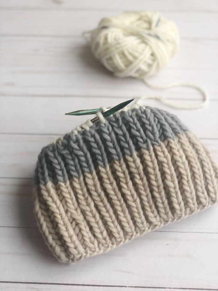 two balls of yarn sitting next to each other on top of a white table with one ball of yarn in the middle