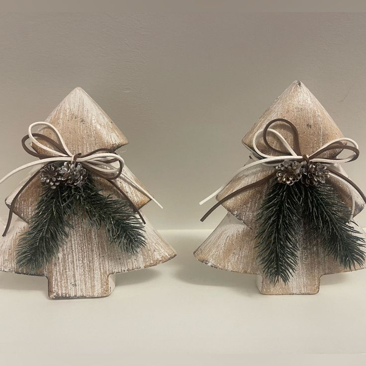 two small wooden christmas trees with bows and pine cones on them, one is made out of wood