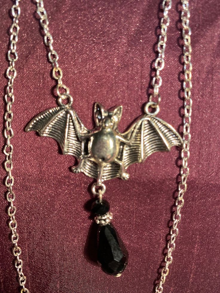 Bat and black gem necklace silver effect Black Vampire Pendant Jewelry, Black Vampire Style Pendant Jewelry, Halloween Black Metal Necklace, Black Halloween Jewelry With Adjustable Chain, Gothic Dangle Necklaces For Parties, Black Pendant Necklace With Chain, Gothic Metal Dangle Necklaces, Gothic Pendant Necklace With Silver Chain, Black Pendant Necklace For Halloween