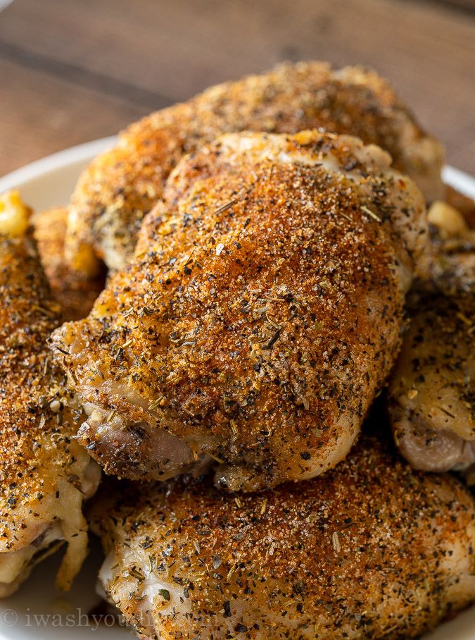 a white plate topped with chicken covered in seasoning on top of a wooden table