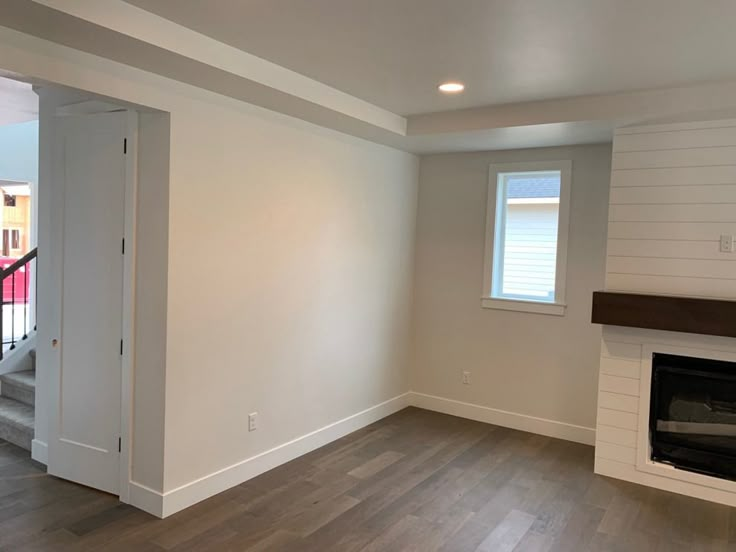 an empty living room with white walls and wood flooring on the hardwood floors in front of a fireplace