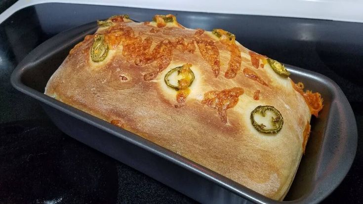 a loaf of bread sitting on top of a pan filled with toppings and sauce