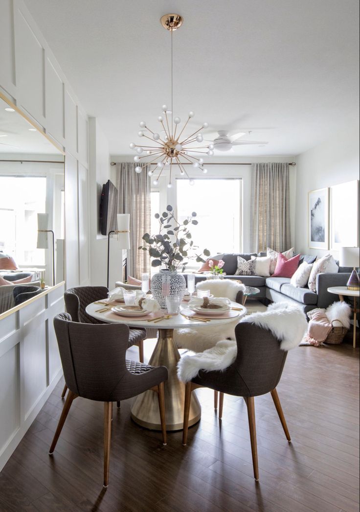 a dining room table with chairs and a chandelier hanging from it's ceiling