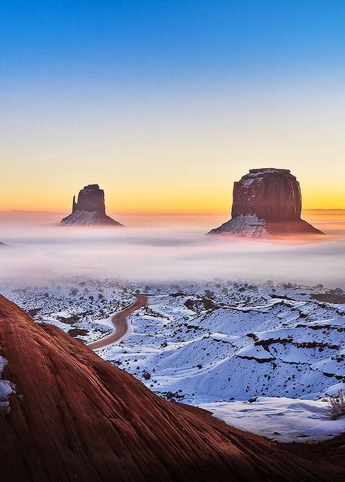 the sun is setting over monument buttes and snow covered ground in wyoming, usa