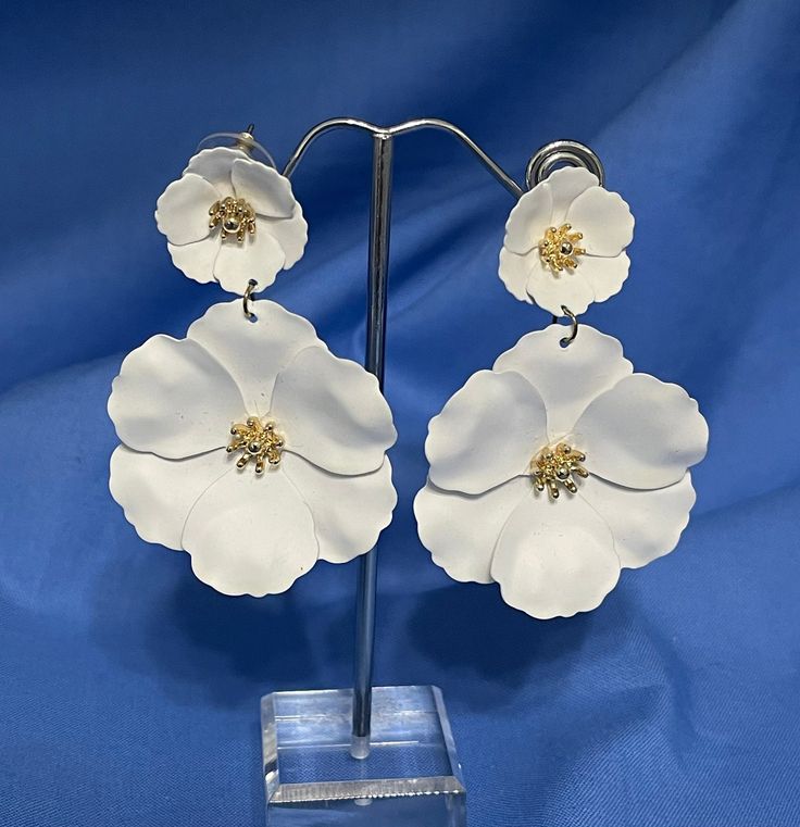 "This is a really pretty pair of white floral flower earrings.  The small flower at the top has the post for pierced ears.  The larger flower dangles from the smaller.  Each blossom has a gold center.  The length is 2 1/2\" and the width, 1 3/4\".    We are not sure what they are made of but they have the feel of soft leather.  They are in very good condition and are just perfect for the bride or summer occasion." Spring Wedding Dangle Earrings, Drop Earrings For Spring Wedding, Spring Wedding Dangle Flower Earrings, White Flower Charm Jewelry For Spring, Spring White Jewelry With Flower Charm, White Dangle Flower Earrings For Spring, Elegant White Flower Earrings, Elegant White Flower Earrings With 3d Details, Elegant White 3d Flower Earrings