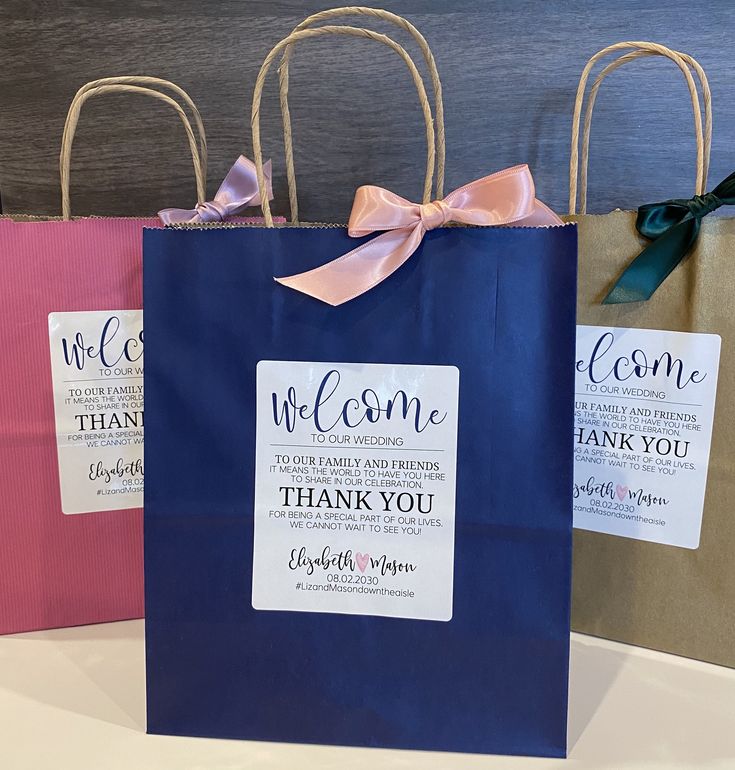 three blue shopping bags with pink bows and thank you tags on them are sitting next to each other